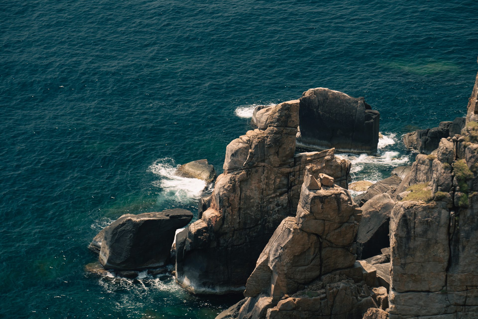 Waves breaking around the rugged coastal rocks below Mũi Điện