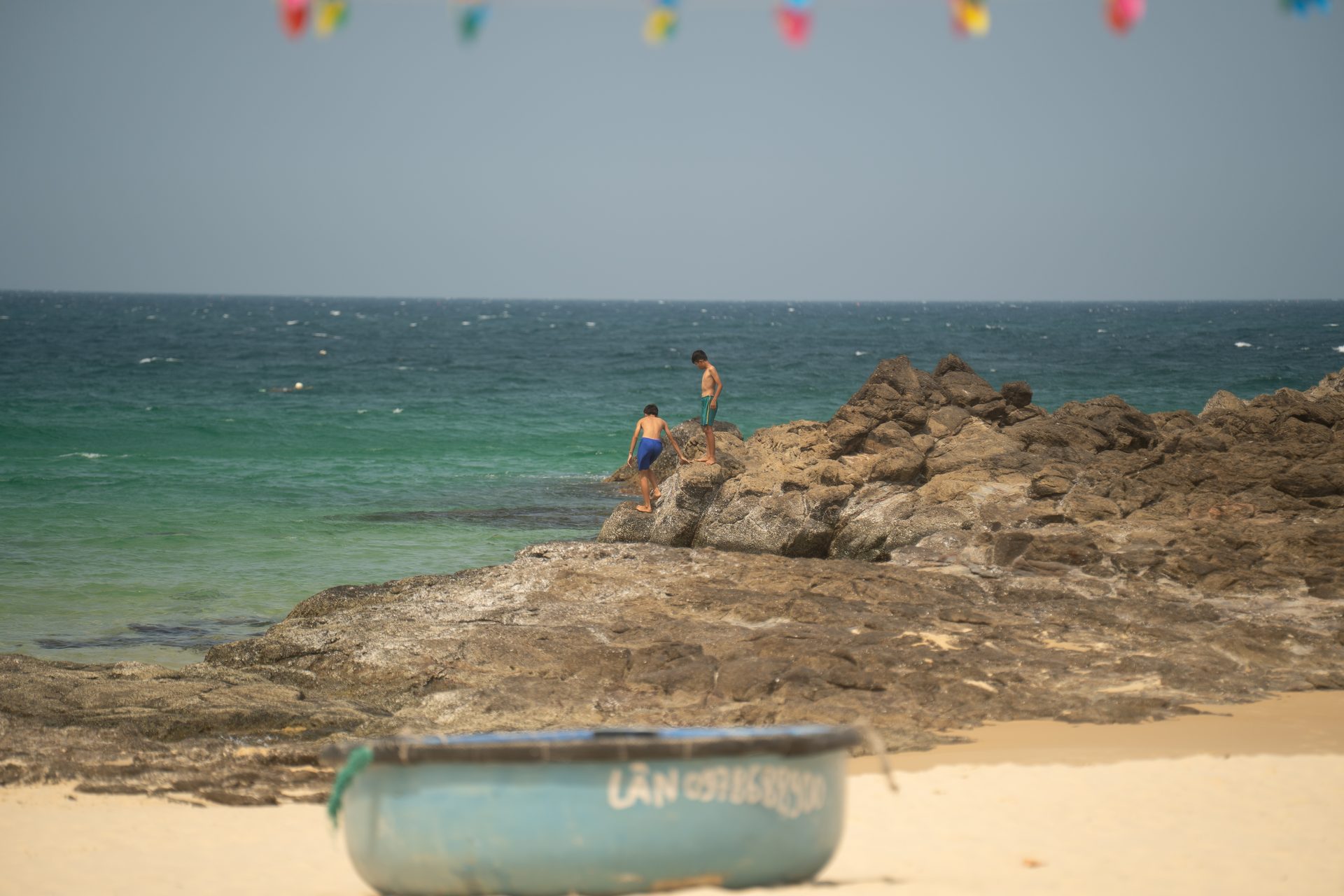 Children from the local fishing community climbing over the rocks for a midday swim near Hòn Yến