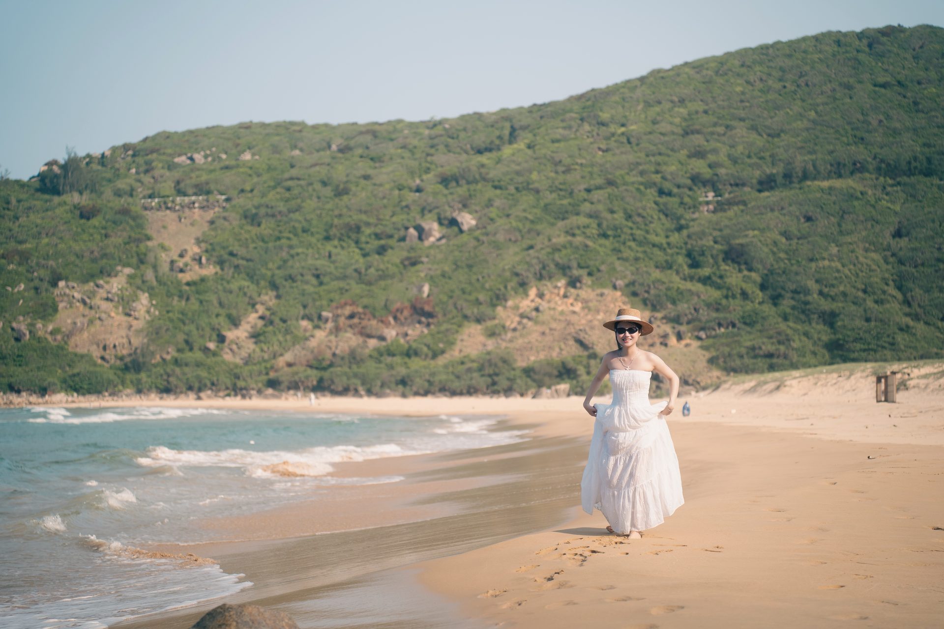 A sunlit portrait on Bãi Môn, a secluded beach sheltered between green hills below the Mũi Điện lighthouse