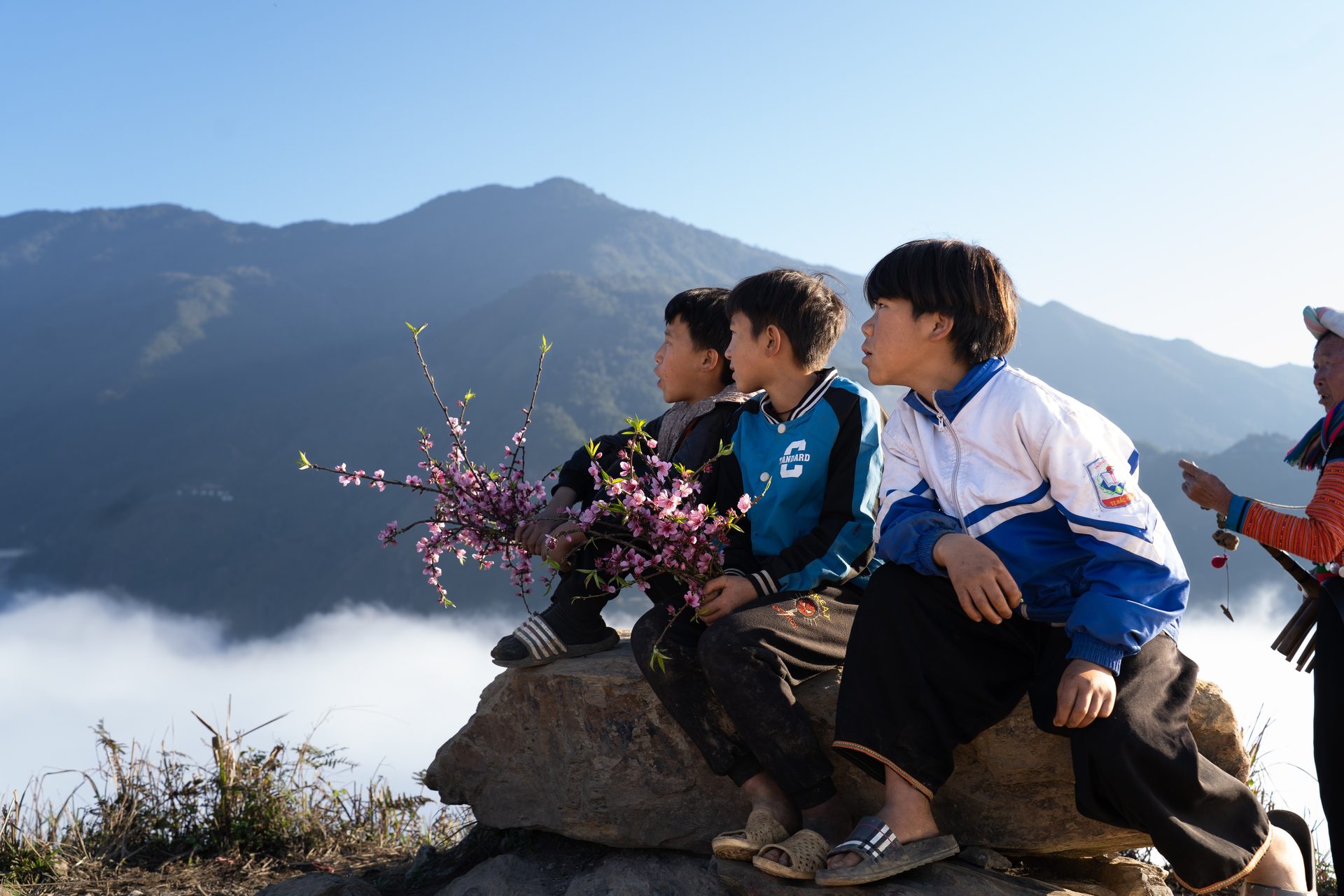 Local children gather peach blossoms to sell to visitors on the Dinosaur Spine